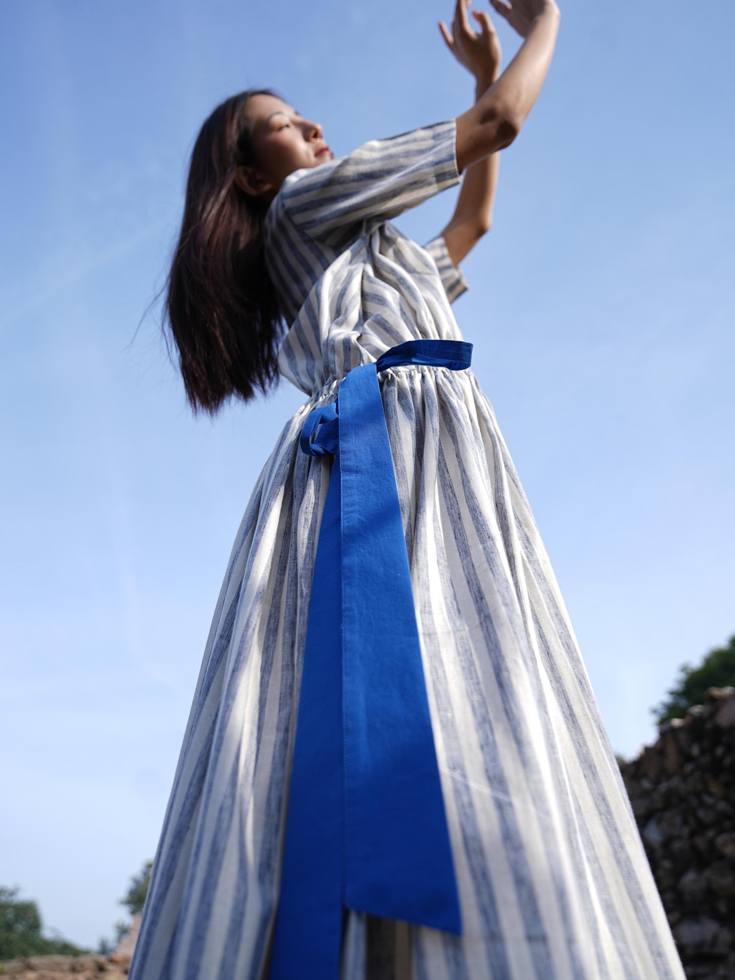 Woman wearing the Sutra Stripe Dress with Button Back — a flowing striped cotton dress with a round neck