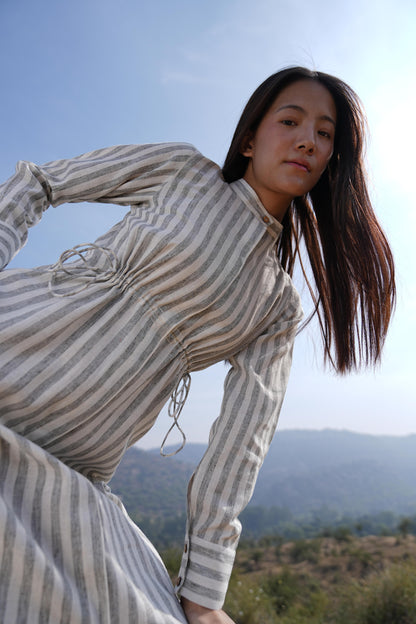 Woman wearing the Sutra Stripe Maxi Dress — a full-length striped cotton dress with a high neck and long sleeves