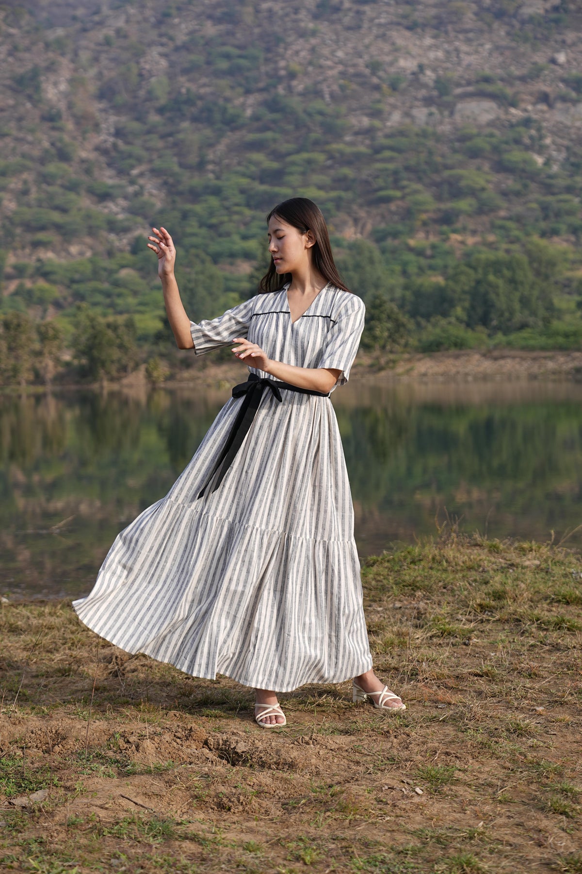 Woman wearing the Sutra Midi Stripe Dress — a striped cotton midi dress with a tiered, flared skirt