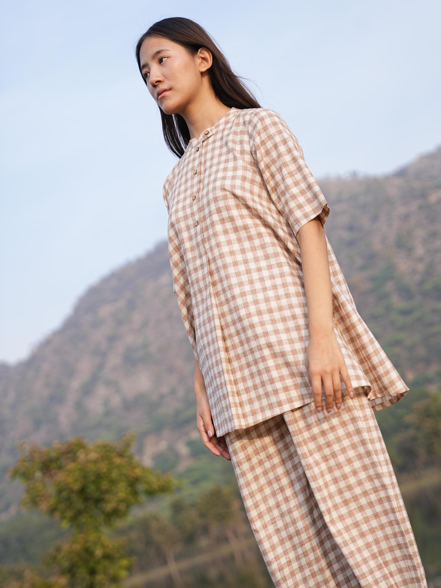 Woman wearing the Sutra Check Mandarin co-ord — a short-sleeve checked cotton tunic with straight-fit pants